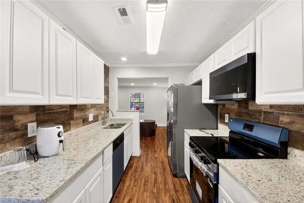 a kitchen with granite countertop a sink a stove and wooden cabinets