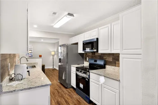 a kitchen with granite countertop a sink stainless steel appliances and white cabinets