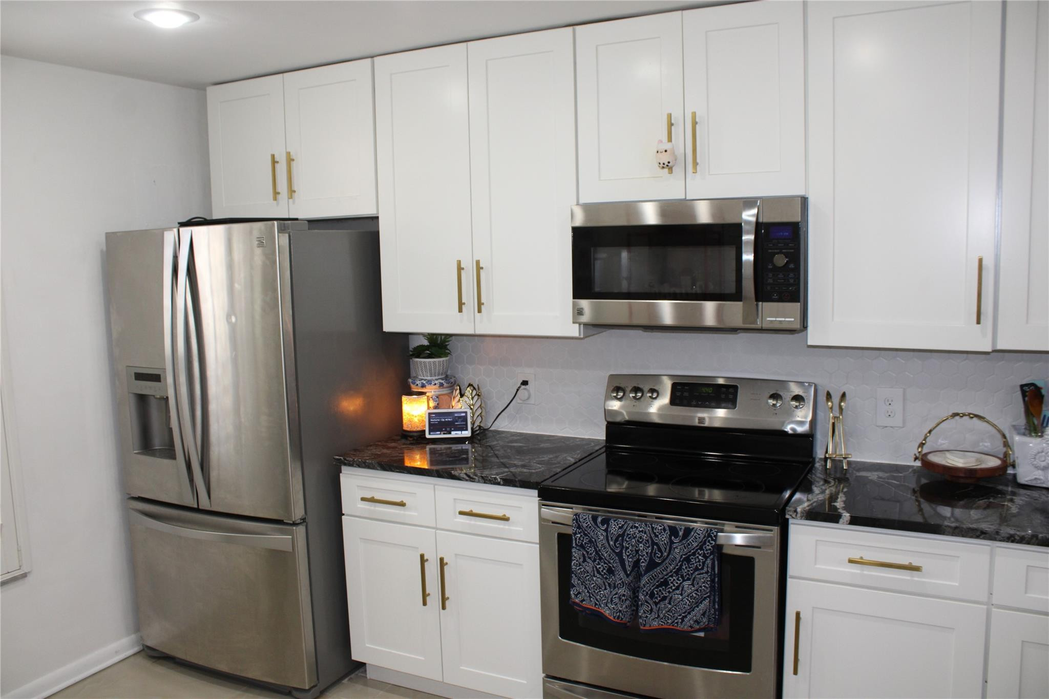 5762 Fox Hollow Drive, Unit G Boca Raton, FL 33486 - Photo 13 of 53 a kitchen with refrigerator a microwave a stove and cabinets