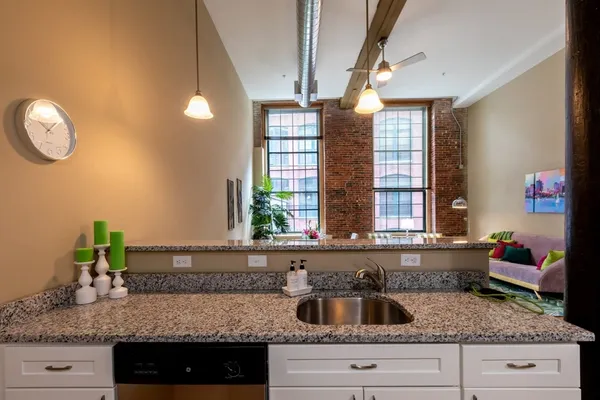 a kitchen with granite countertop a sink and a white wooden cabinets