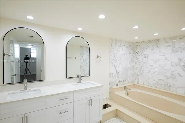 a spacious bathroom with a double vanity sink a mirror and a bathtub