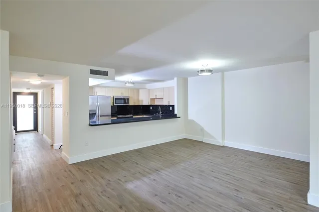 a view of kitchen and refrigerator in wooden floor
