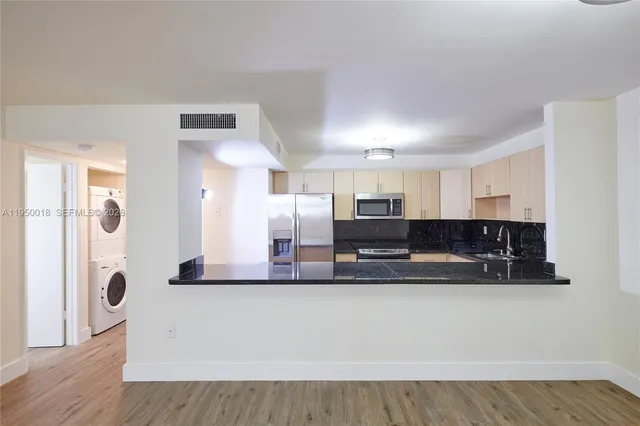 a kitchen with stainless steel appliances granite countertop a refrigerator a sink and a granite countertops with wooden floor