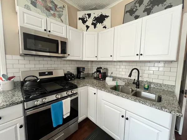 a kitchen with stainless steel appliances granite countertop white cabinets a stove a sink and dishwasher