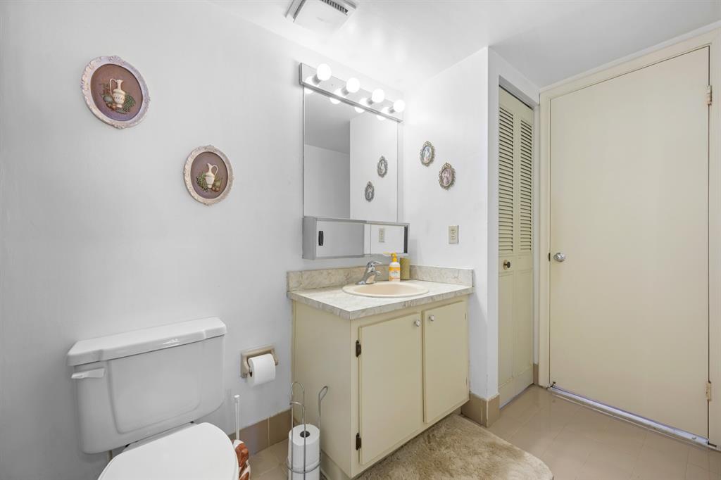 1301 Northeast 7th Street, Unit 113 Hallandale Beach, FL 33009 - Photo 16 of 45 a bathroom with a granite countertop sink a toilet and a mirror