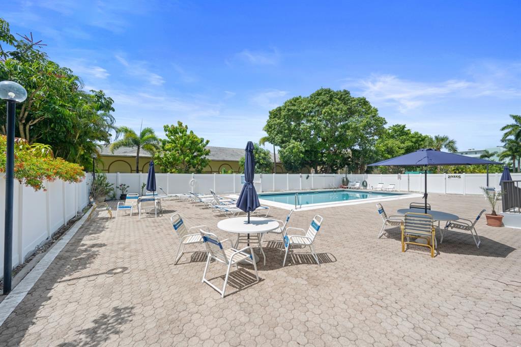 1301 Northeast 7th Street, Unit 113 Hallandale Beach, FL 33009 - Photo 5 of 45 a view of a patio with a table and chairs under an umbrella with wooden fence