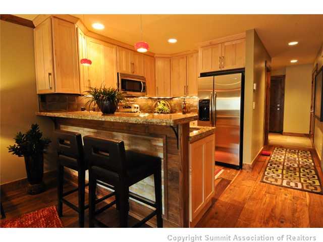 487 Main Street, Unit D Frisco, CO 80443 - Photo 5 of 25 a kitchen with stainless steel appliances granite countertop a table chairs and a refrigerator