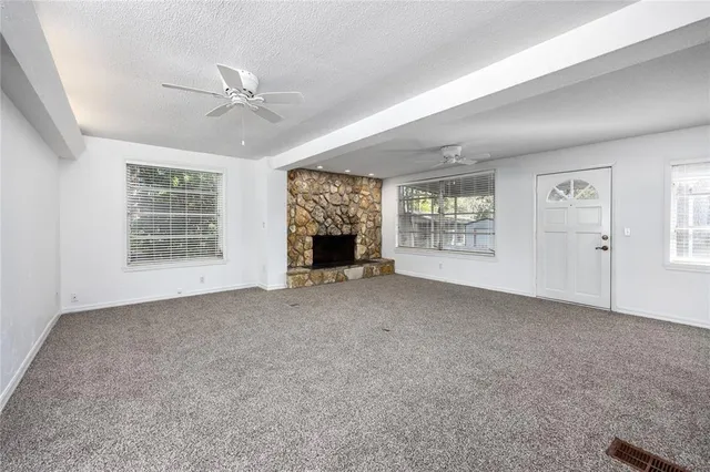 an empty room with windows and chandelier fan