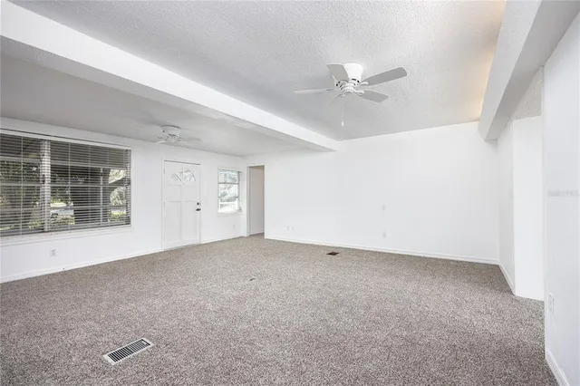 an empty room with windows and fan