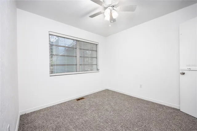 an empty room with a window and a ceiling fan