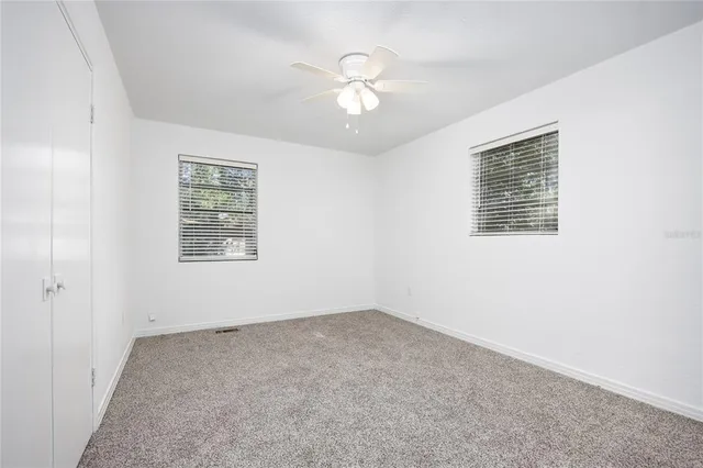 an empty room with a window and a fan