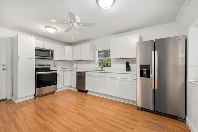 a kitchen with a refrigerator a sink and dishwasher with wooden floor