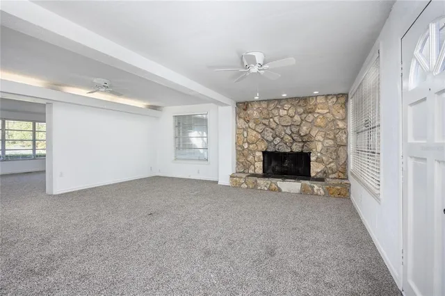 an empty room with windows and fireplace