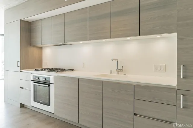 a large white kitchen with granite countertop a sink and dishwasher a stove with wooden floor