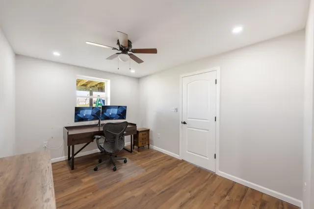 a workspace with wooden floor and a chandelier fan