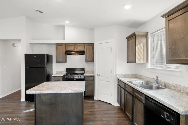 a kitchen with a stove a sink a refrigerator and cabinets