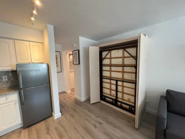 a kitchen with a refrigerator and wooden floor