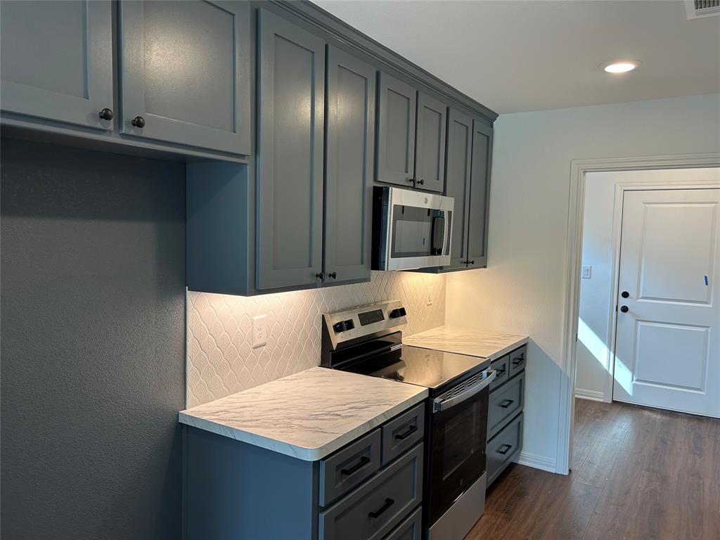 412 Conway Street Waco, TX 76705 - Photo 5 of 8 Kitchen with appliances with stainless steel finishes, light countertops, dark wood-style flooring, backsplash, and recessed lighting
