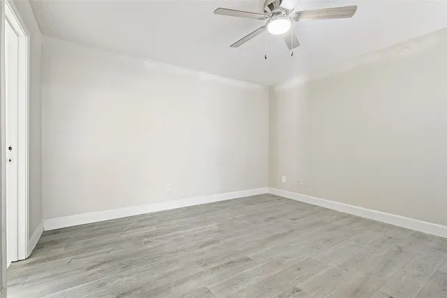 an empty room with wooden floor and ceiling fan
