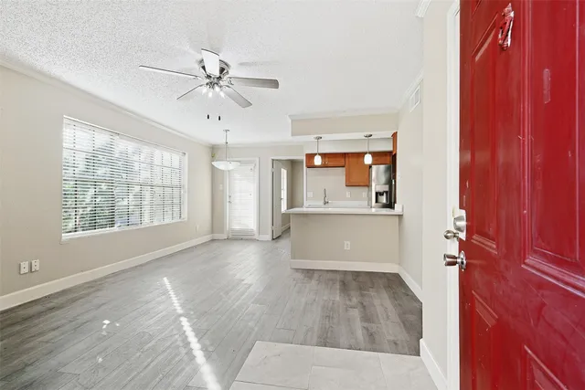 an empty room with windows fireplace and fan