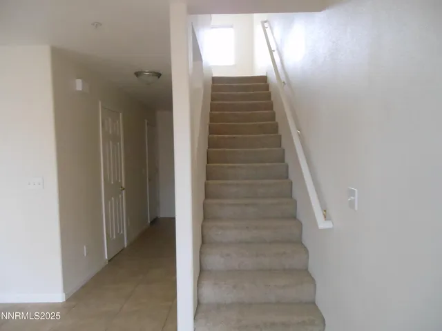 a view of staircase with white walls and white door