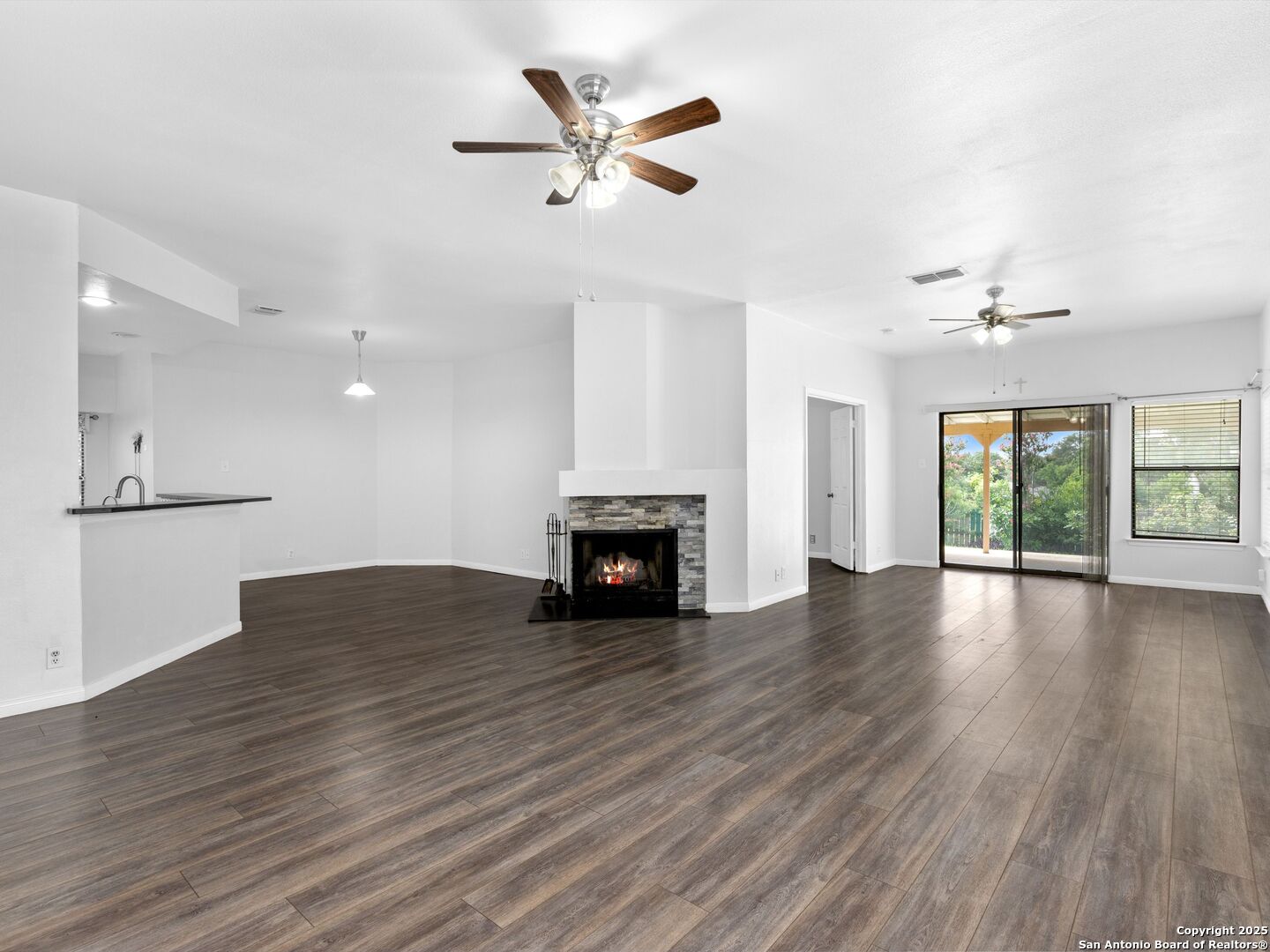 5430 Vista Court San Antonio, TX 78247 - Photo 7 of 37 an empty room with wooden floor a ceiling fan a fireplace and windows