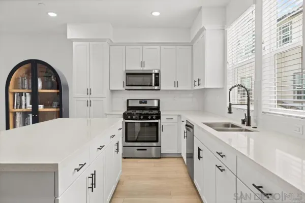 a kitchen with granite countertop a sink stainless steel appliances and white cabinets