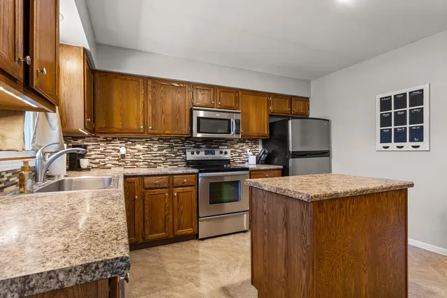 a kitchen with granite countertop wooden cabinets a stove top oven and stainless steel appliances