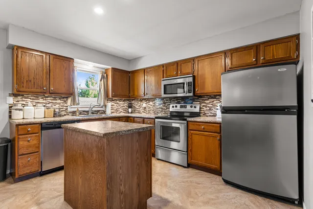 a kitchen with granite countertop stainless steel appliances a refrigerator cabinets and a window