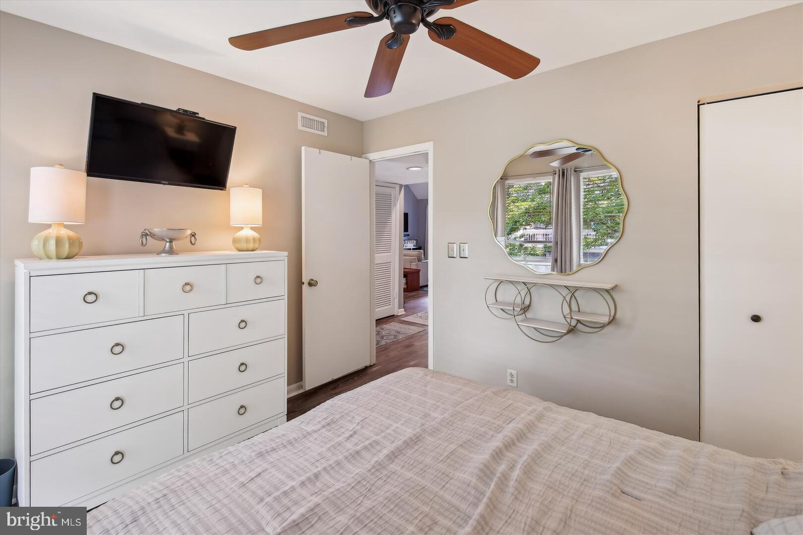 39689 Round Robin Way, Unit 3103 Bethany Beach, DE 19930 - Photo 18 of 34 a bedroom with a bed a flat tv screen and a chandelier