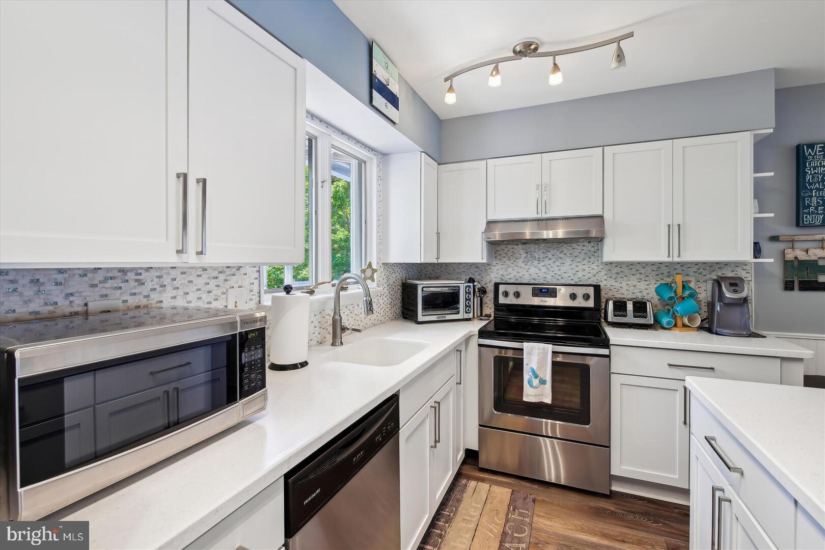 39689 Round Robin Way, Unit 3103 Bethany Beach, DE 19930 - Photo 9 of 34 a kitchen with stainless steel appliances white cabinets and white appliances