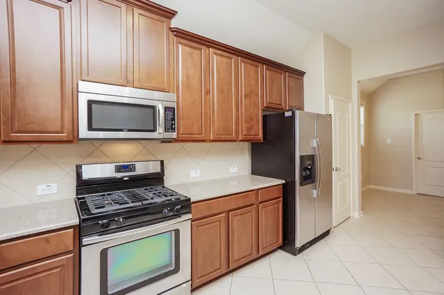 a kitchen with stainless steel appliances granite countertop a stove microwave refrigerator and sink