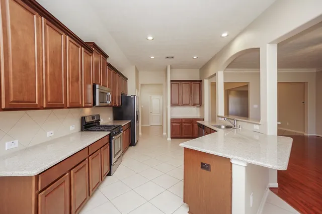 a large kitchen with stainless steel appliances a sink dishwasher stove and cabinets