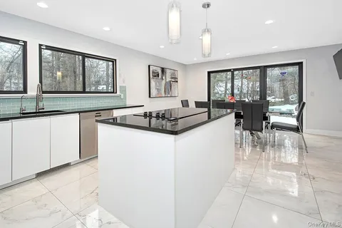 a kitchen with granite countertop a stove a sink a dining table and chairs