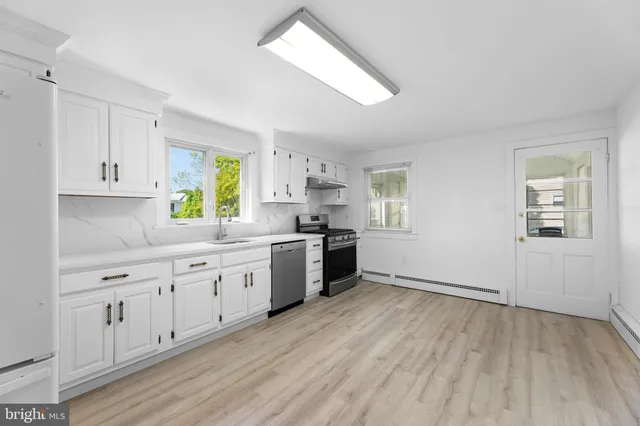 a kitchen with granite countertop white cabinets a sink a window and stainless steel appliances