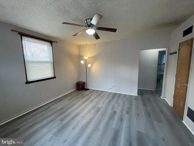 an empty room with wooden floor cabinet and windows