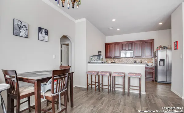 a kitchen with stainless steel appliances granite countertop a dining table chairs refrigerator and cabinets