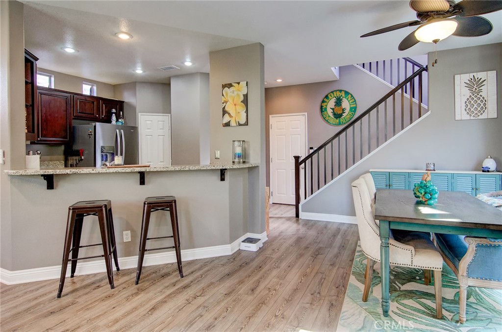 13069 Arborwalk Lane Tustin, CA 92782 - Photo 15 of 47 a kitchen with stainless steel appliances kitchen island granite countertop a table chairs in it and wooden floors