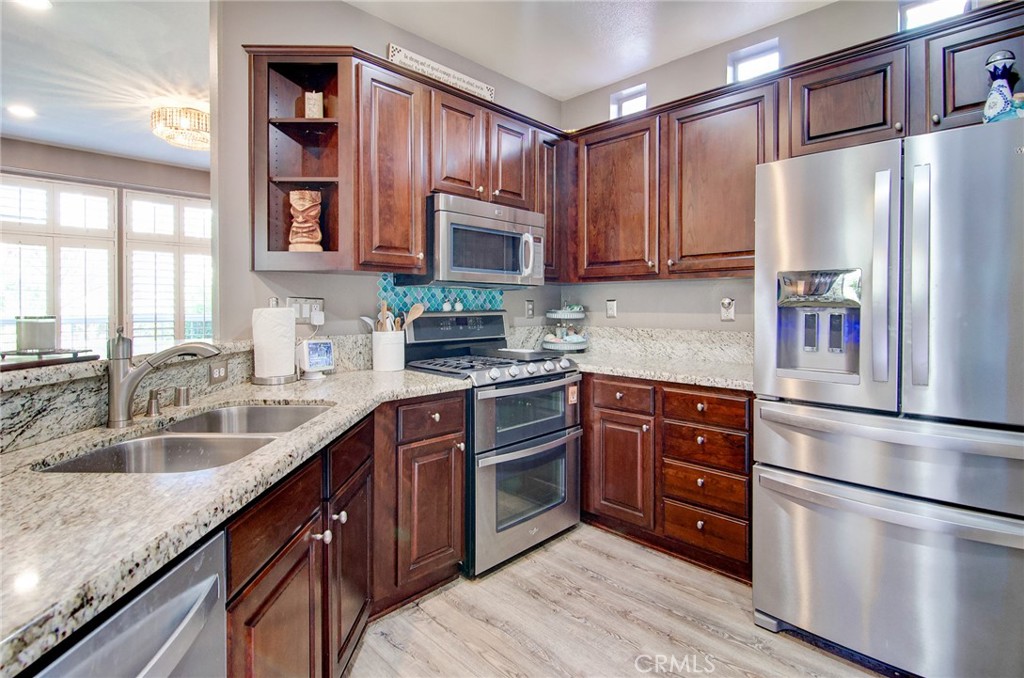 13069 Arborwalk Lane Tustin, CA 92782 - Photo 18 of 47 a kitchen with stainless steel appliances granite countertop a refrigerator sink and cabinets