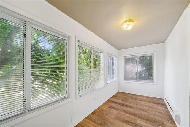 a view of an empty room with wooden floor and a window