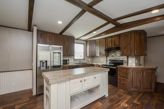 a kitchen with stainless steel appliances granite countertop a sink stove microwave and refrigerator