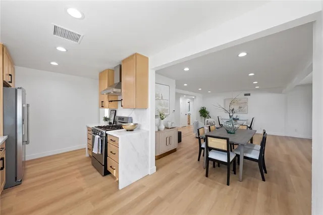 a kitchen with stainless steel appliances a dining table chairs stove refrigerator and cabinets