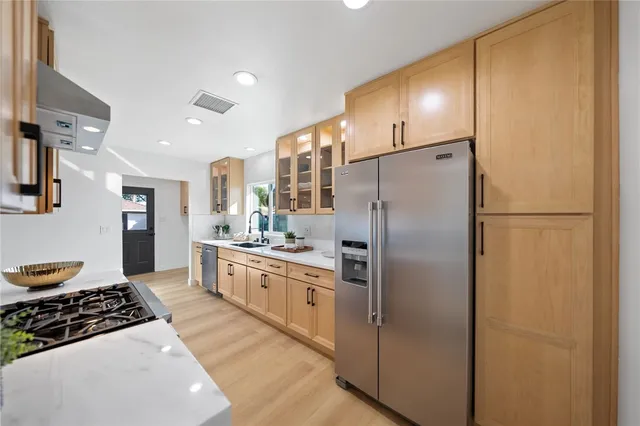 a large kitchen with stainless steel appliances granite countertop a refrigerator and a stove top oven
