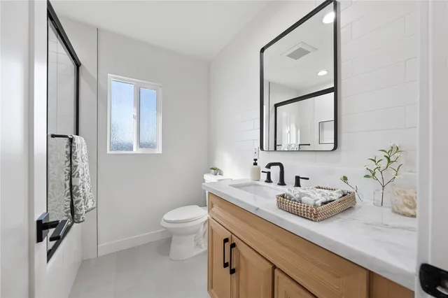 a bathroom with a granite countertop sink a toilet and a mirror