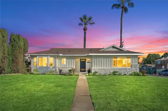 a front view of a house with a yard and potted plants