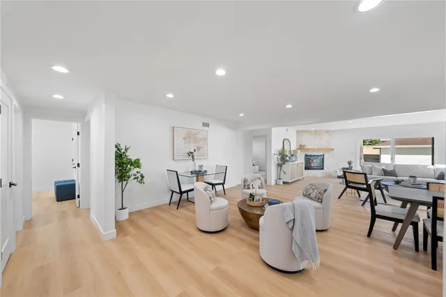 a living room with lots of white furniture and a wooden floor