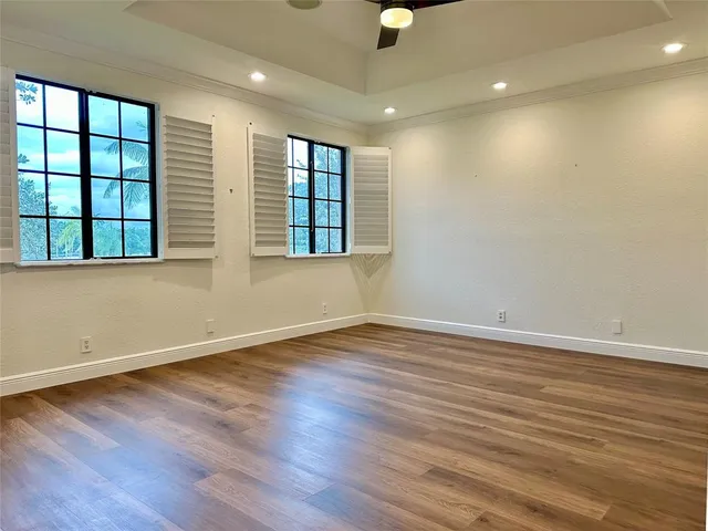 an empty room with wooden floor and windows