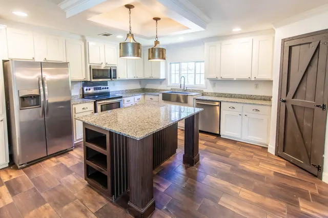 a kitchen with kitchen island granite countertop a sink stove and refrigerator