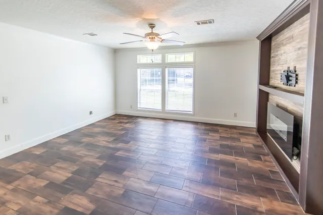 a view of an empty room with a window and wooden floor
