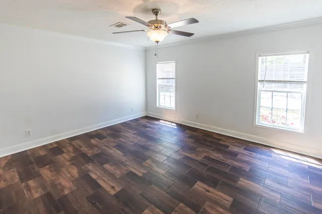 a view of an empty room with wooden floor and a window